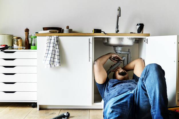 Plumber fixing kitchen sink.